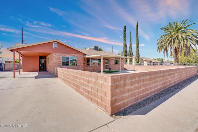 ranch-style home featuring brick siding, an attached carport, a chimney, and fence