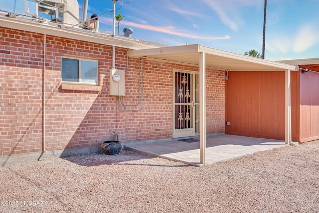 rear view of house with brick siding and a patio