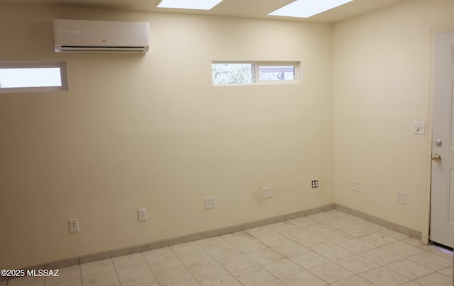basement with a healthy amount of sunlight, light tile patterned flooring, baseboards, and an AC wall unit