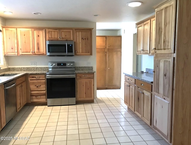 kitchen with light tile patterned flooring, light stone counters, and appliances with stainless steel finishes
