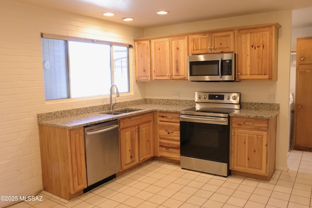 kitchen featuring recessed lighting, appliances with stainless steel finishes, light tile patterned flooring, a sink, and light stone counters