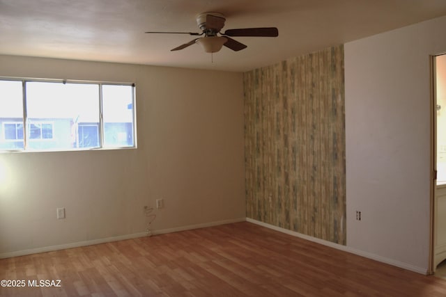 empty room featuring baseboards, wood finished floors, and ceiling fan