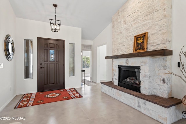 foyer entrance with lofted ceiling, finished concrete floors, and a fireplace