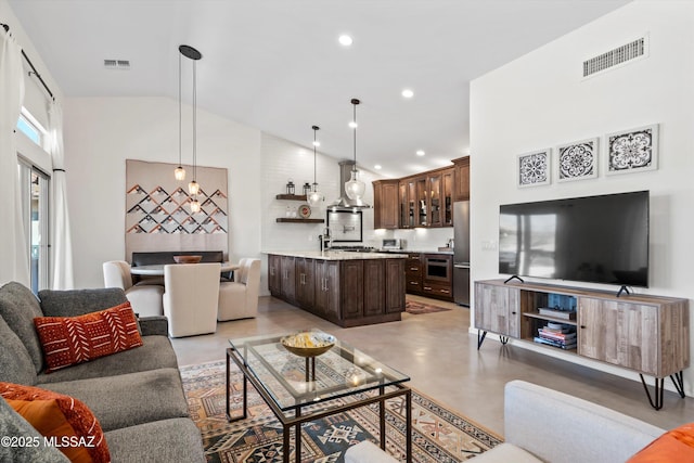 living area featuring finished concrete flooring, visible vents, and high vaulted ceiling