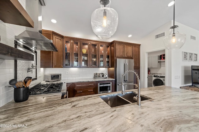 kitchen with visible vents, range with gas cooktop, high quality fridge, washer / clothes dryer, and a sink