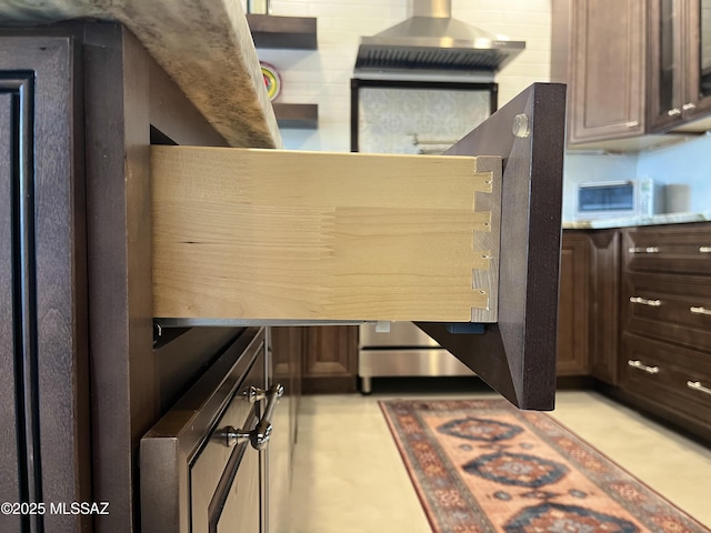 kitchen with dark brown cabinetry and wall chimney range hood