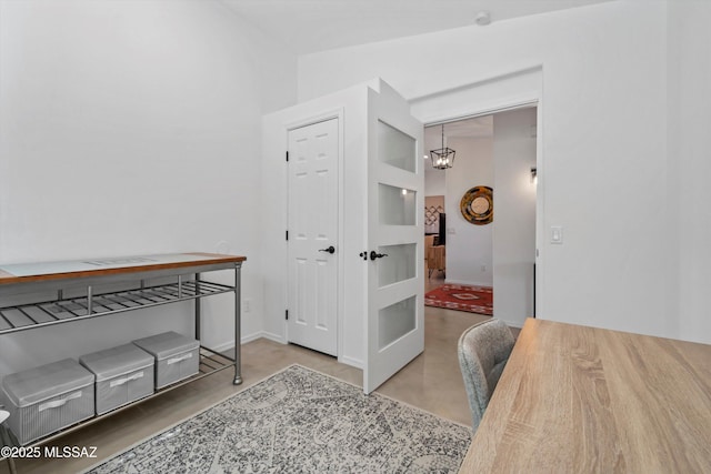 home office with finished concrete floors, baseboards, and an inviting chandelier