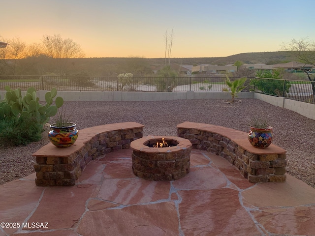 patio terrace at dusk featuring a fire pit and a fenced backyard