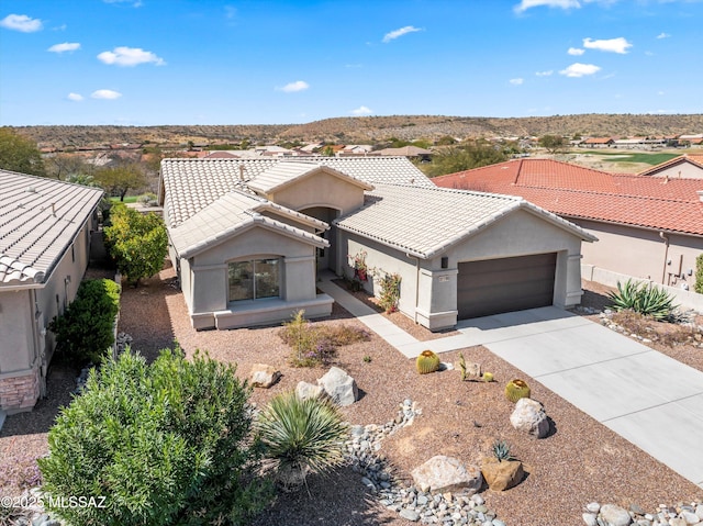 view of front of property featuring fence, a tiled roof, stucco siding, driveway, and an attached garage