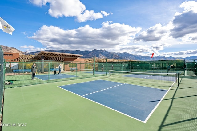 view of tennis court with a mountain view and fence