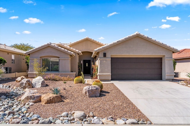 view of front of home with a tile roof, an attached garage, driveway, and stucco siding