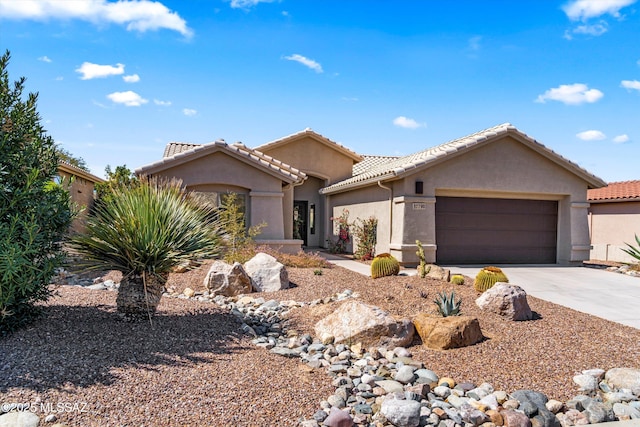 single story home with stucco siding, a garage, driveway, and a tile roof