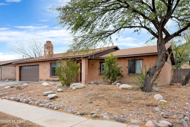 ranch-style house with fence, a chimney, concrete driveway, a garage, and brick siding