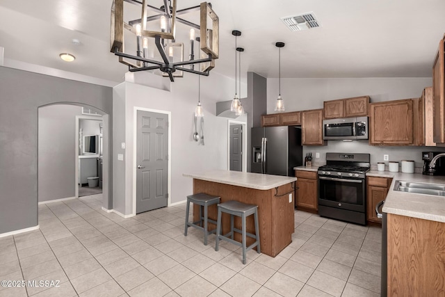 kitchen with visible vents, a sink, a kitchen island, stainless steel appliances, and arched walkways