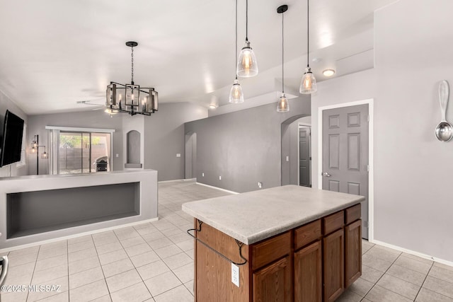 kitchen featuring open floor plan, pendant lighting, vaulted ceiling, light tile patterned floors, and arched walkways