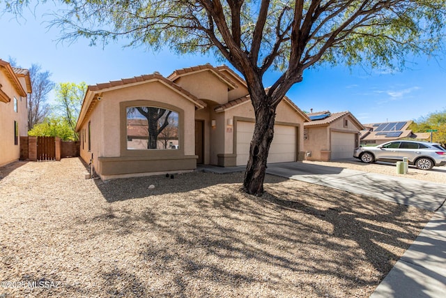 view of front of house featuring stucco siding, concrete driveway, an attached garage, and fence