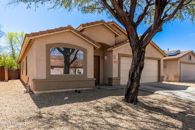 view of front of house with stucco siding, fence, concrete driveway, a garage, and a tiled roof