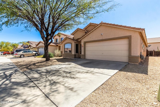 view of front facade with stucco siding, a tile roof, fence, concrete driveway, and an attached garage