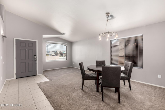 dining space featuring visible vents, a chandelier, vaulted ceiling, light carpet, and light tile patterned floors