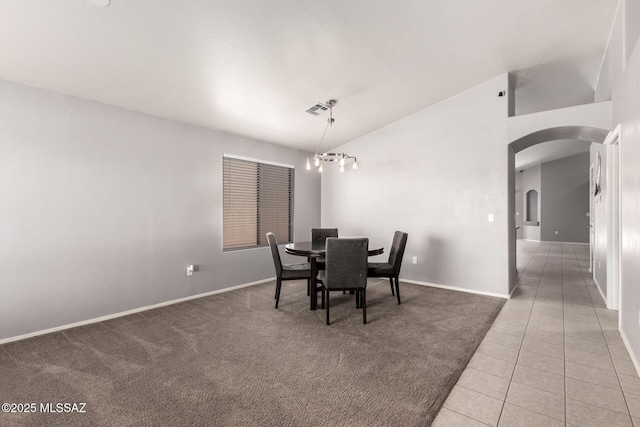 dining area with visible vents, light colored carpet, lofted ceiling, light tile patterned floors, and arched walkways