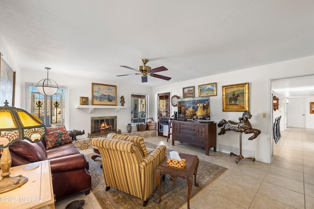 living room with light tile patterned floors, baseboards, ceiling fan, and a glass covered fireplace