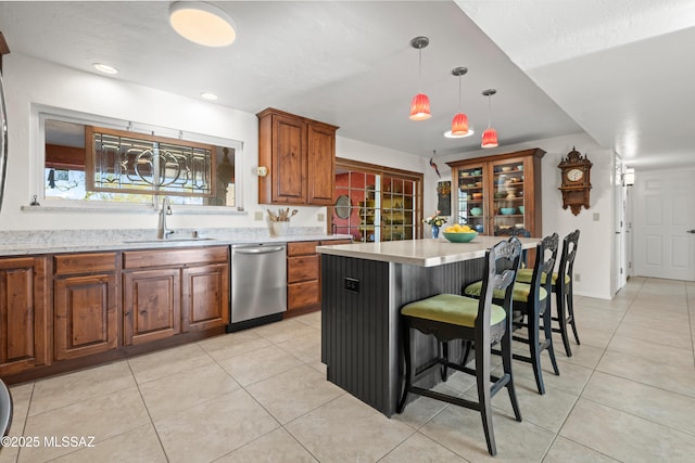 kitchen with stainless steel dishwasher, light tile patterned floors, a sink, and light countertops