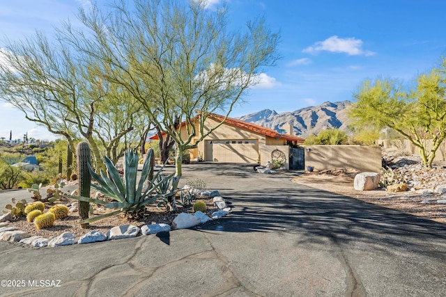 mediterranean / spanish house with an attached garage, stucco siding, a mountain view, and driveway