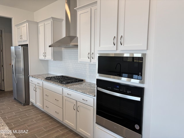 14722 E Sands Ranch Rd, Vail, AZ 85641 - kitchen with appliances with stainless steel finishes, wall chimney exhaust hood, wood finished floors, light stone countertops, and tasteful backsplash