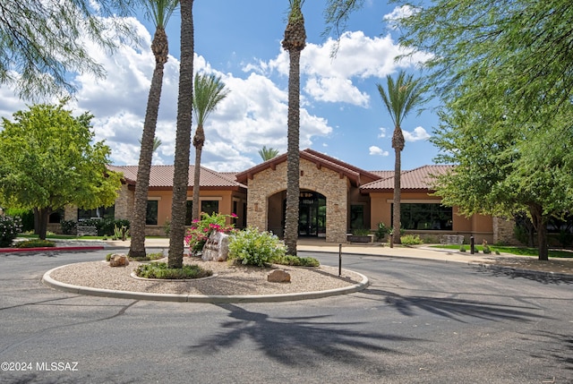 view of front of property with a tiled roof, stone siding, and stucco siding