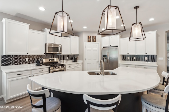 kitchen with a sink, stainless steel appliances, a breakfast bar, and white cabinetry