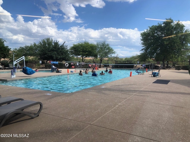 pool with a patio area and fence