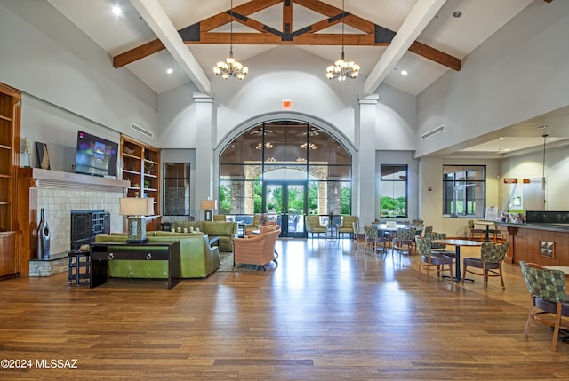 living room with wood finished floors, a notable chandelier, a fireplace with raised hearth, and high vaulted ceiling