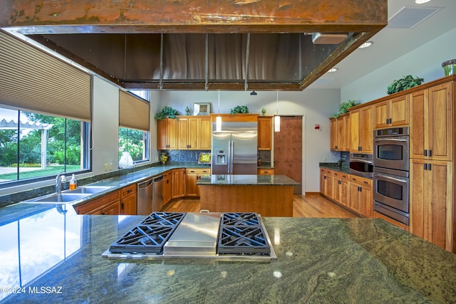 kitchen with tasteful backsplash, light wood-type flooring, a high ceiling, stainless steel appliances, and a sink