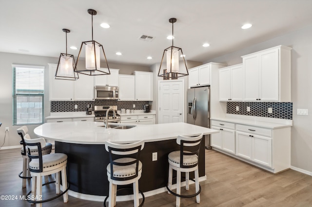 kitchen with visible vents, light wood finished floors, a center island with sink, appliances with stainless steel finishes, and light countertops