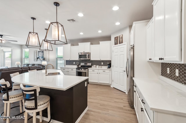 kitchen with visible vents, a sink, stainless steel appliances, light countertops, and a kitchen breakfast bar