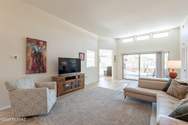 living room with baseboards, a towering ceiling, and light wood finished floors