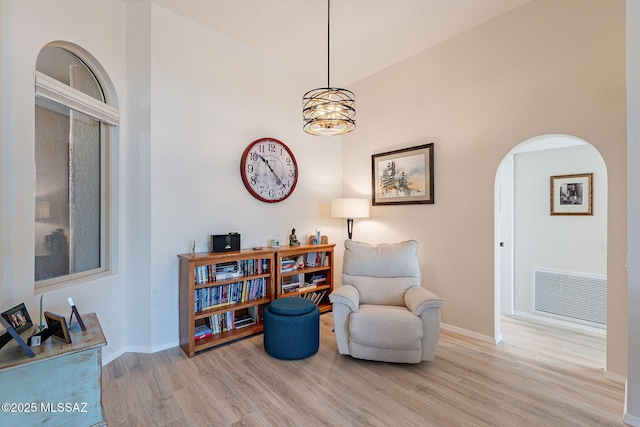 sitting room with visible vents, arched walkways, baseboards, and wood finished floors