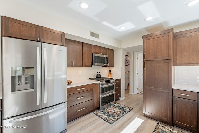 kitchen featuring visible vents, stainless steel appliances, decorative backsplash, light countertops, and light wood-style floors