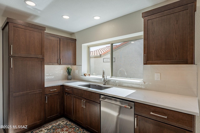 kitchen featuring light stone counters, a sink, decorative backsplash, dark brown cabinets, and stainless steel dishwasher