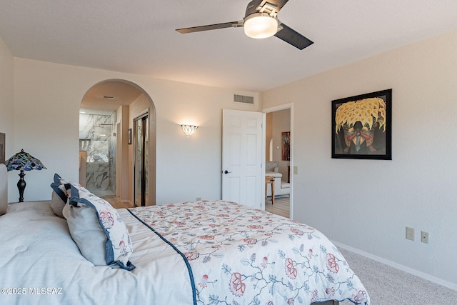 bedroom with visible vents, light carpet, a ceiling fan, arched walkways, and baseboards