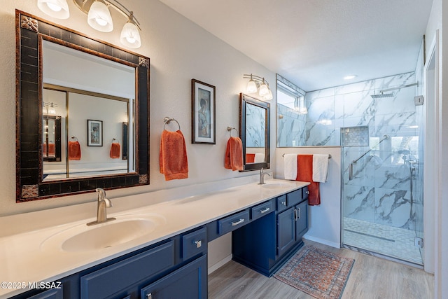 bathroom featuring a sink, a marble finish shower, and wood finished floors