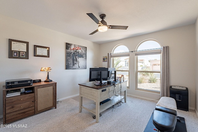 office space featuring baseboards, light colored carpet, and ceiling fan