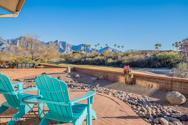 view of patio with a mountain view and fence