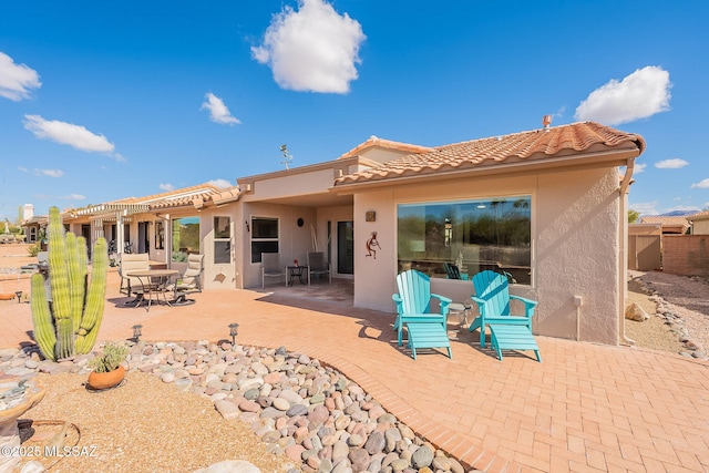 back of property featuring outdoor dining space, stucco siding, a tiled roof, and a patio