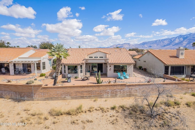 view of front of house with stucco siding, a tile roof, a pergola, a patio, and a mountain view