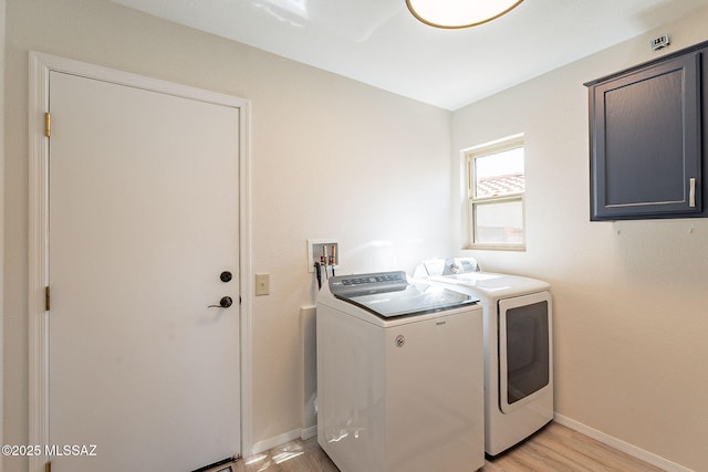 clothes washing area with laundry area, light wood-style flooring, baseboards, and washer and clothes dryer