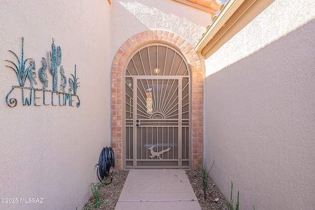 entrance to property with stucco siding and a gate