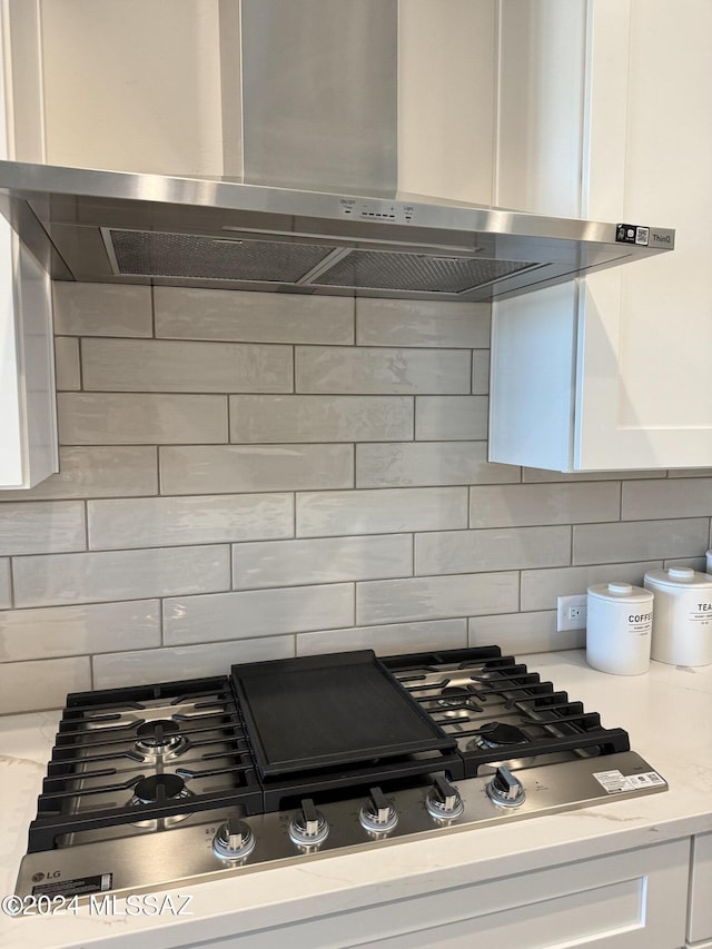 kitchen with white cabinetry, backsplash, and wall chimney range hood