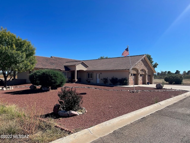 view of front of property with a tiled roof, stone siding, stucco siding, and driveway