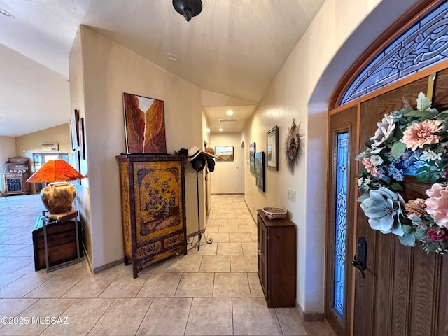 hall with baseboards, lofted ceiling, and light tile patterned flooring